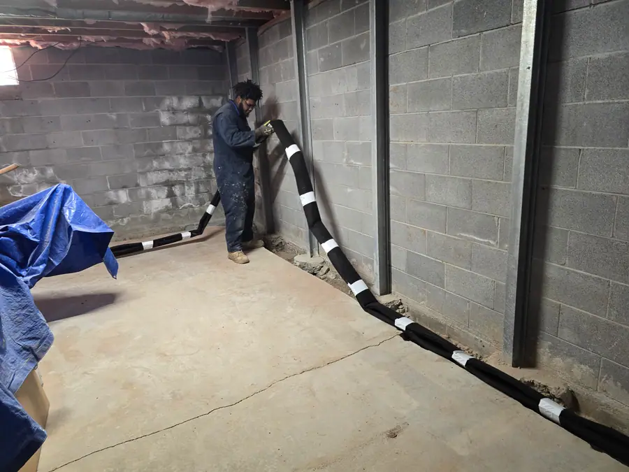 A Rozier Pest Control & Waterproofing technician installing interior drainage system in a basement.