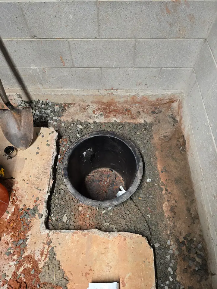 A Rozier Pest Control & Waterproofing crew installing a sump pump pit for basement waterproofing services.