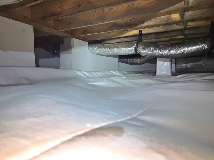 A Rozier Pest Control & Waterproofing crew installing a clean crawl space vapor barrier and adjustable support jacks.