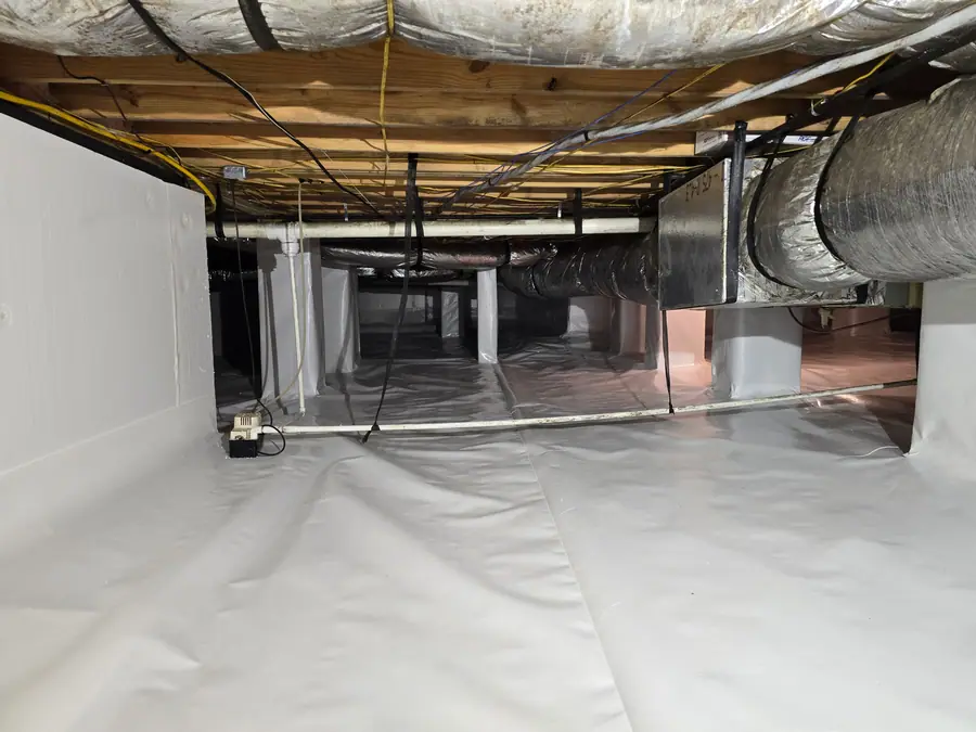 A Rozier Pest Control & Waterproofing crew installing a clean white vapor barrier system in a residential crawl space.
