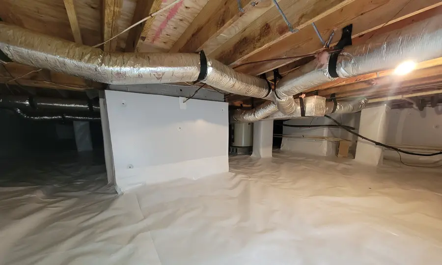 A completed crawl space encapsulation by Rozier Pest Control & Waterproofing, with a bright white vapor barrier across the floor and up the piers.