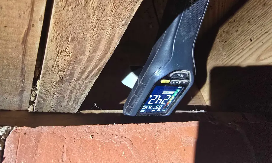 A Rozier Pest Control & Waterproofing technician taking a moisture reading on crawl space joists.