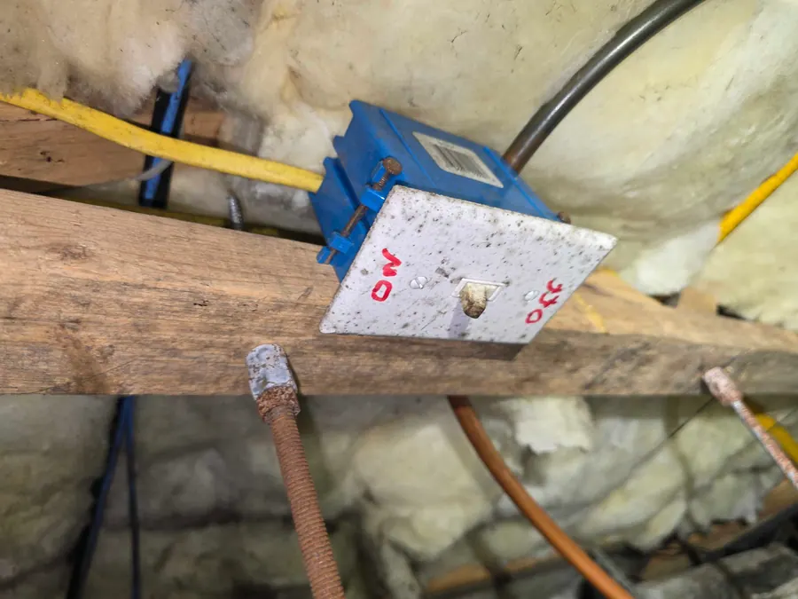 Electrical wiring and a junction box running along a joist above the insulation.