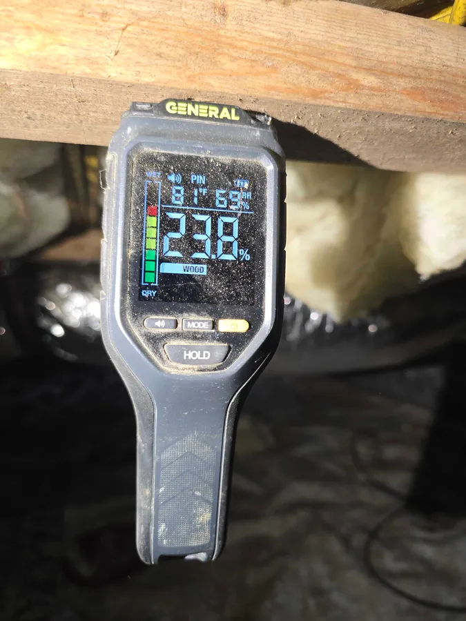 A Rozier Pest Control & Waterproofing technician taking a wood moisture reading with a digital meter.