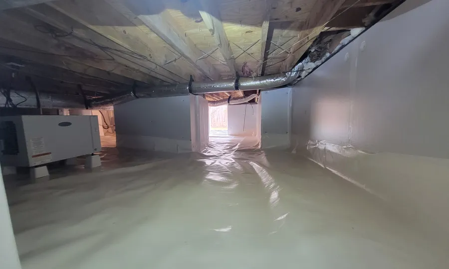 A Rozier Pest Control & Waterproofing crawl space encapsulation with a white vapor barrier and a dehumidifier in place.