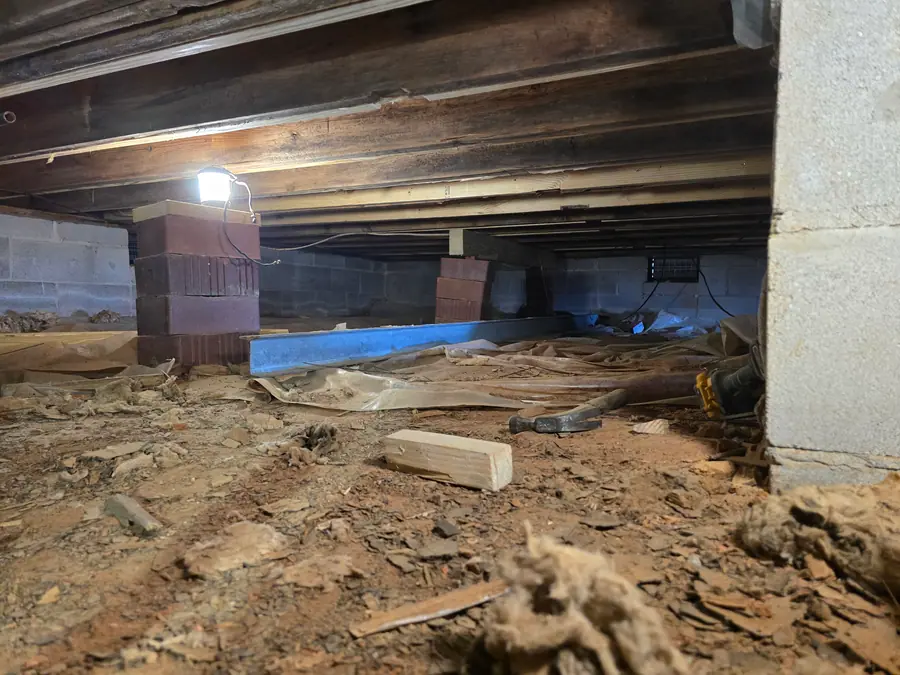 A Rozier Pest Control & Waterproofing crew reinforcing a crawl space with new brick piers and a steel support beam.