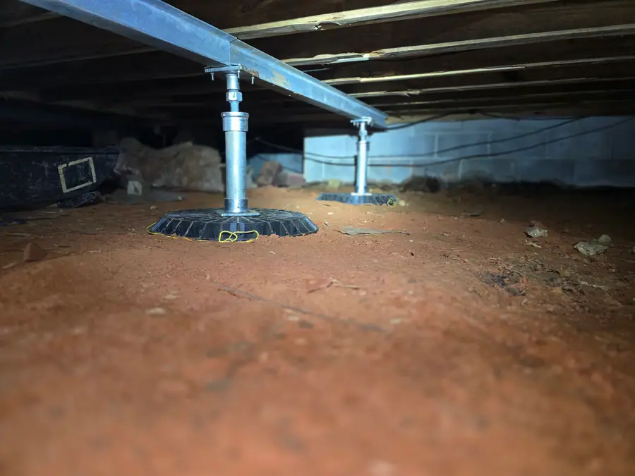 A Rozier Pest Control & Waterproofing crew installing adjustable support jacks to support a sagging floor in a crawl space.