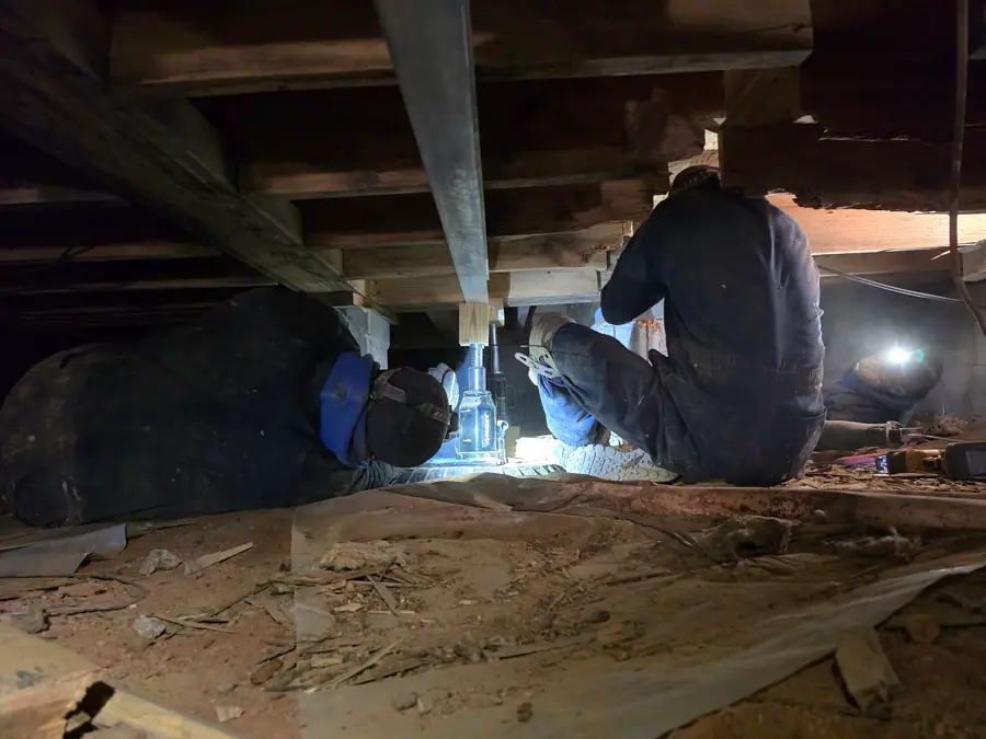 A Rozier Pest Control & Waterproofing crew installing adjustable support jacks to stabilize a crawl space and repair sagging floors.