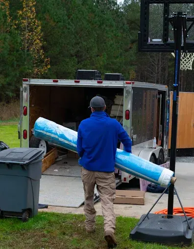 A Rozier Pest Control & Waterproofing crew member carrying a large roll of vapor barrier to the work trailer.