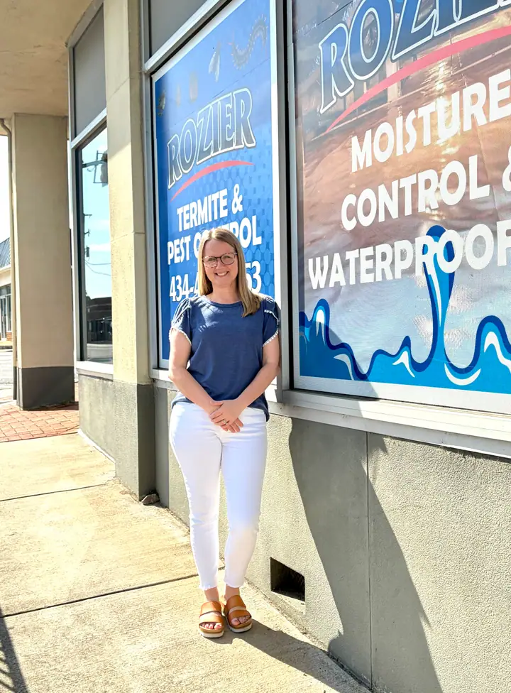 A Rozier Pest Control & Waterproofing team member standing in front of the branded office building windows.