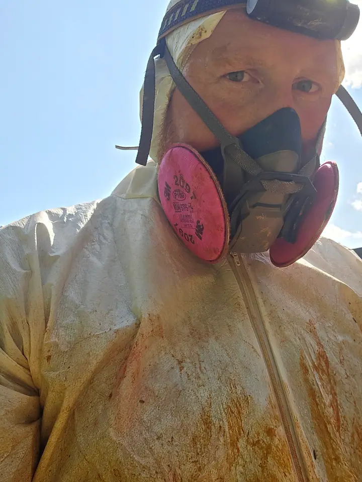 A Rozier Pest Control & Waterproofing team member in a respirator and protective suit.