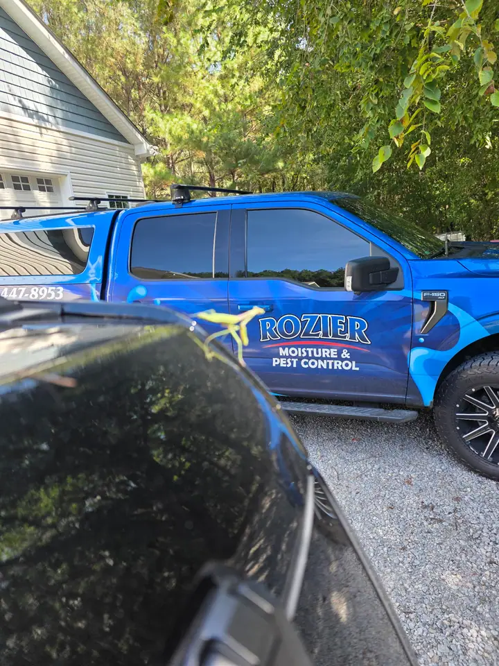 A Rozier Pest Control & Waterproofing branded service vehicle, a blue Ford F-150 truck with company logo.