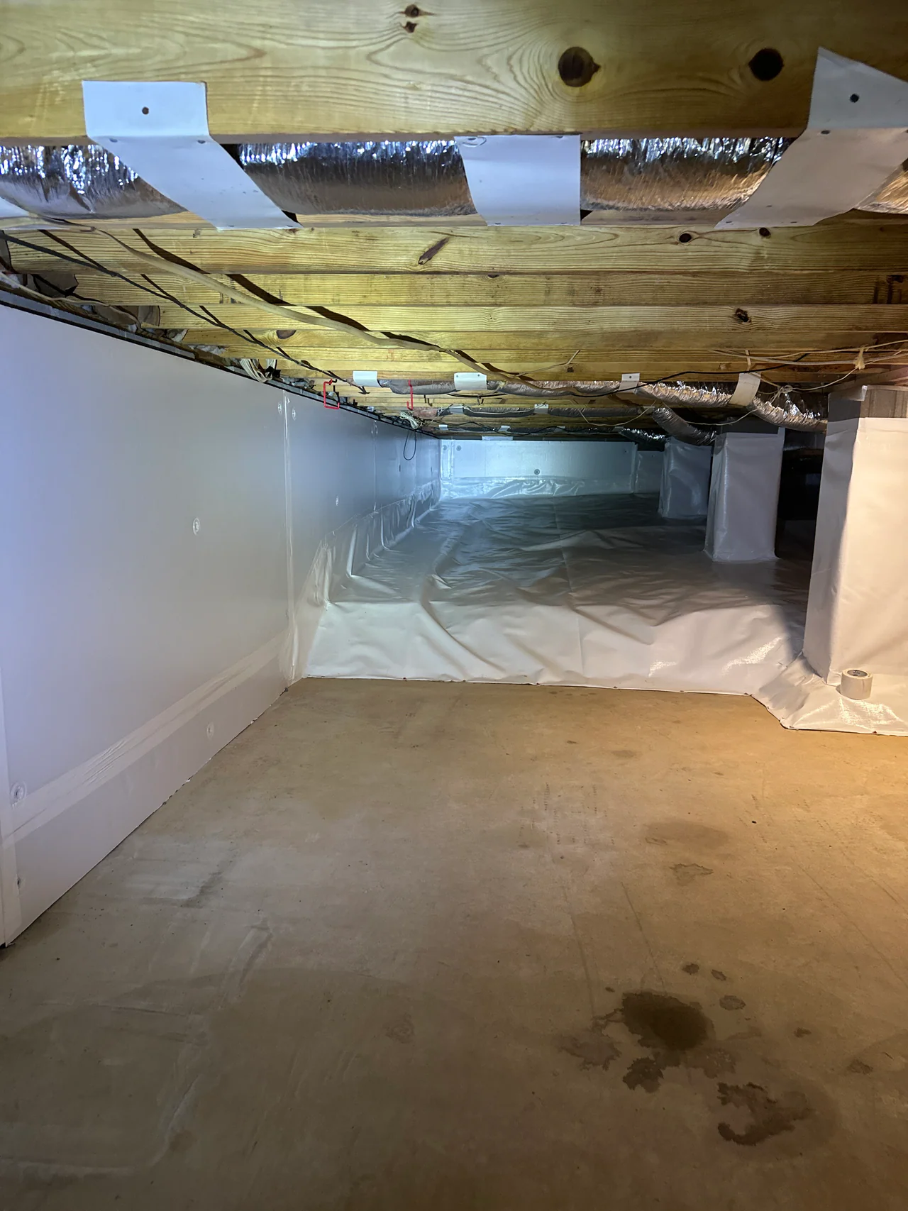 Rozier Pest Control & Waterproofing completing crawl space encapsulation with a bright white vapor barrier system.