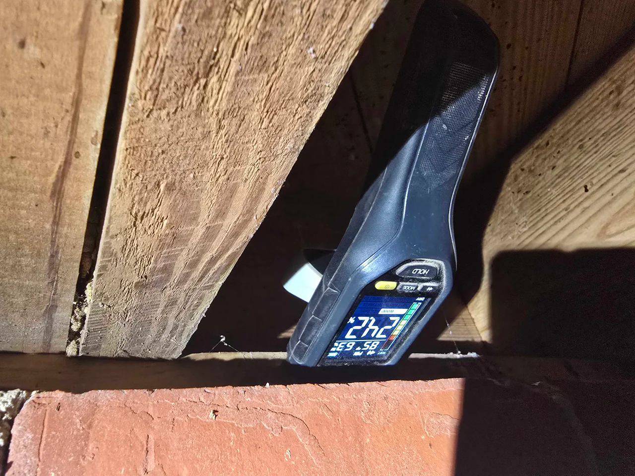 Rozier Pest Control & Waterproofing technician using a moisture meter to detect hidden moisture in crawl space wood.