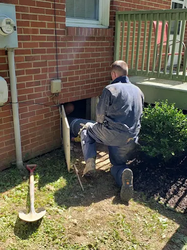 Rozier Pest Control & Waterproofing installing a new crawl space access door in a brick foundation.