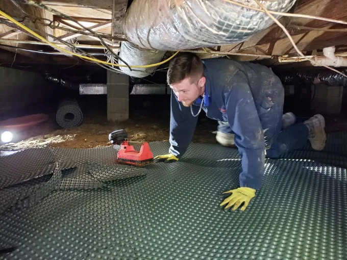 Rozier Pest Control & Waterproofing technician installing drainage matting in a crawl space.