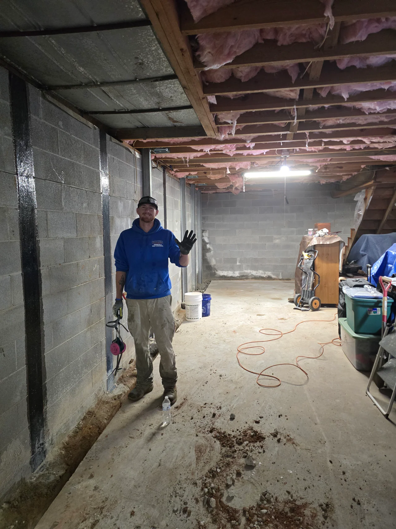 Rozier Pest Control & Waterproofing technician in a basement with carbon fiber wall reinforcement and interior drainage system.
