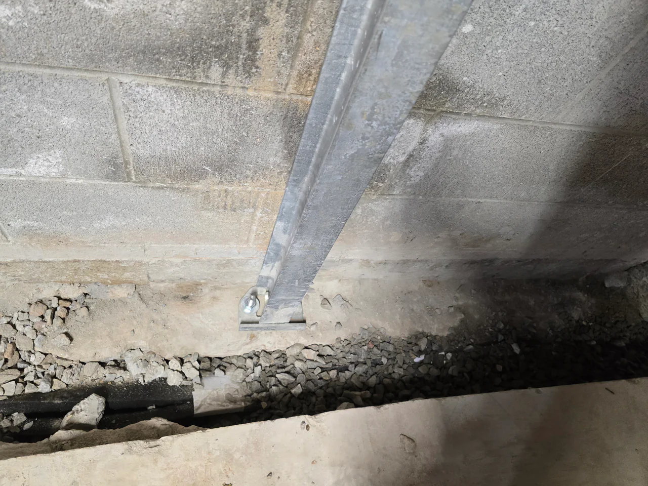 Rozier Pest Control & Waterproofing inspecting an interior basement wall with a bowing wall repair system installed.