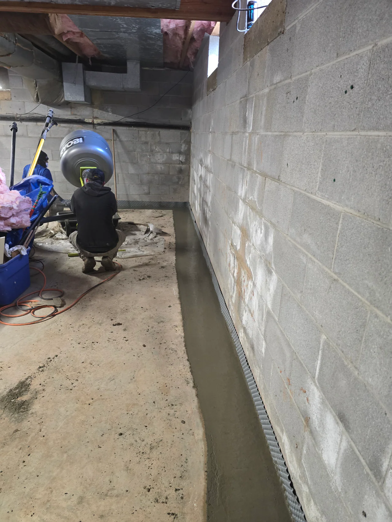 Rozier Pest Control & Waterproofing installing an interior drainage system in a basement with visible efflorescence.
