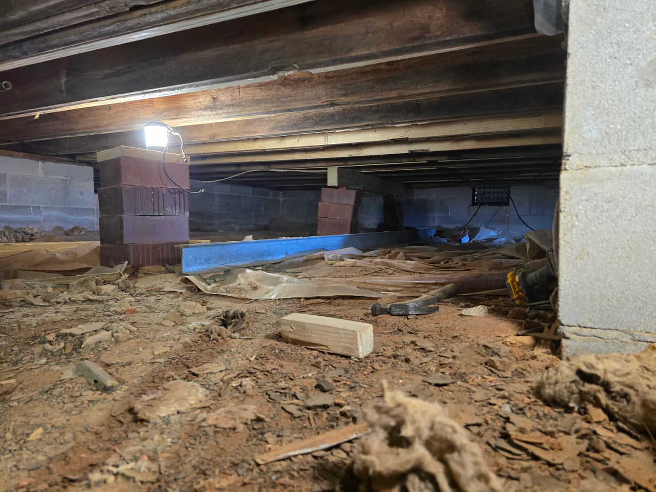 Rozier Pest Control & Waterproofing reinforcing a crawl space with new brick piers and a steel support beam.