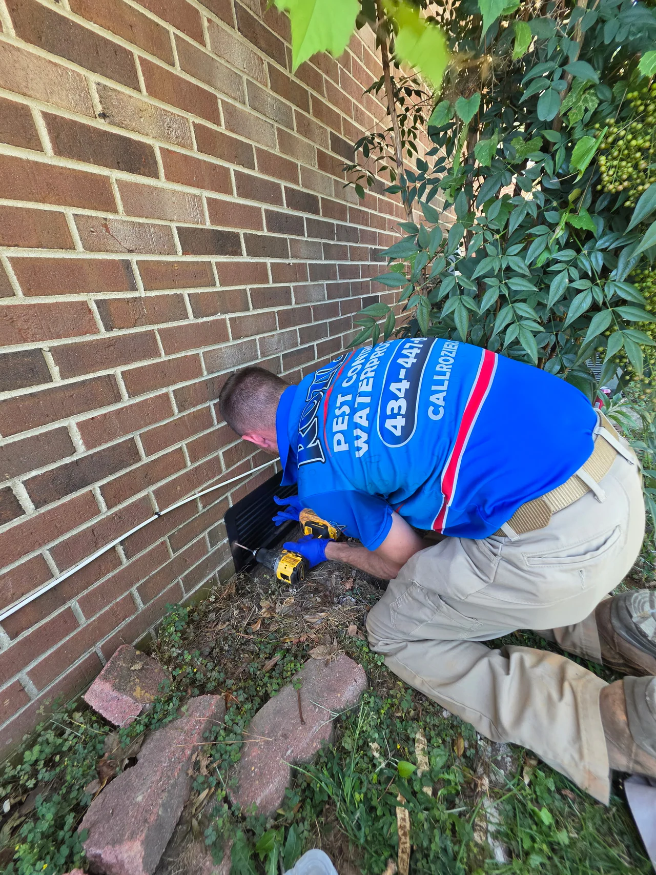 Rozier Pest Control & Waterproofing technician installing pest exclusion at a home's exterior foundation